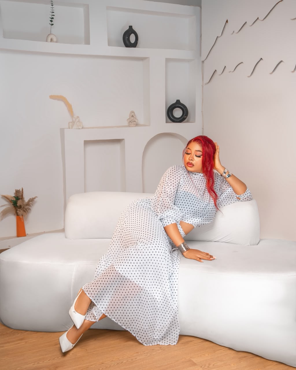 Woman with red hair reclining on a sculpted white couch