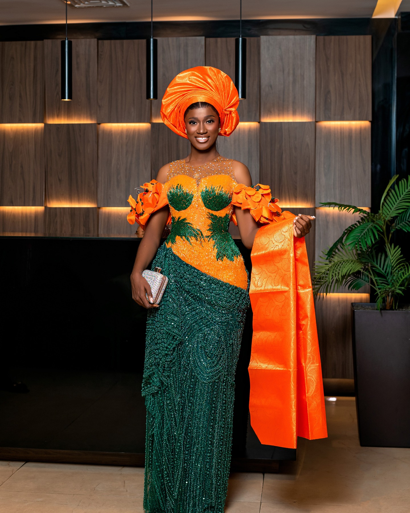 Woman in an orange gele and green beaded gown