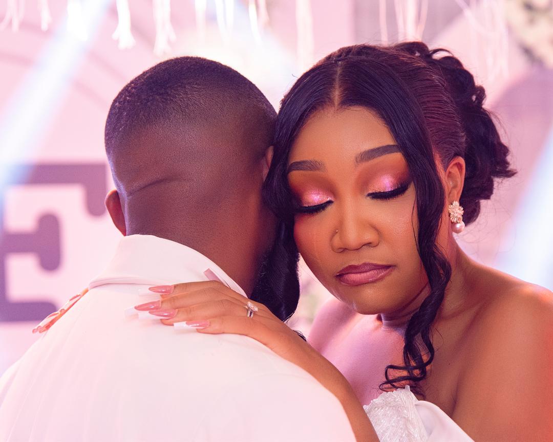 Close embrace of a wedding couple in pink light