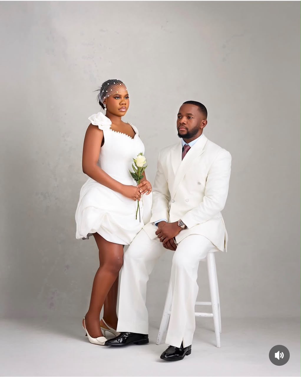Studio portrait of a couple dressed in white with a single rose