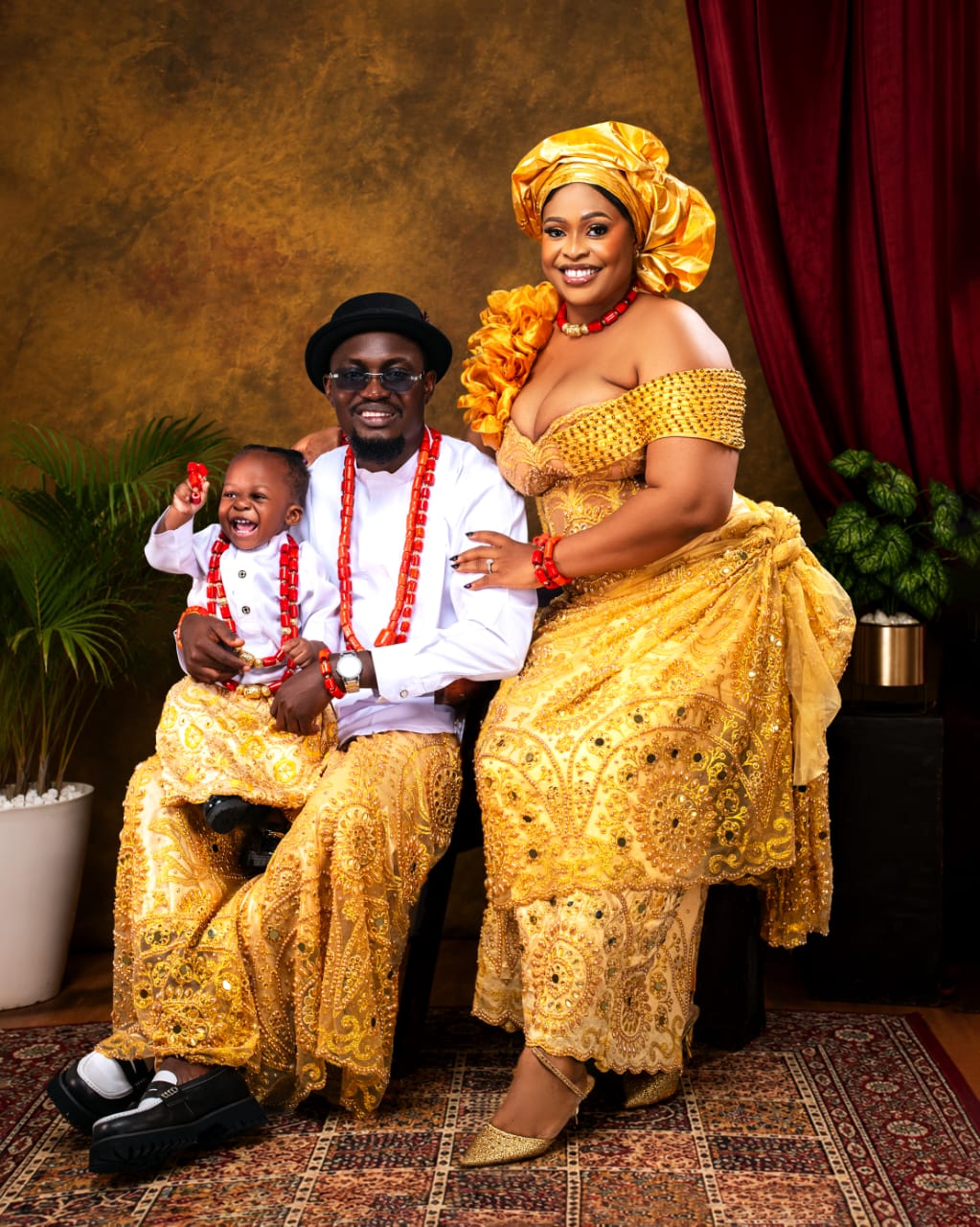 Family in golden lace and coral beads with a laughing toddler