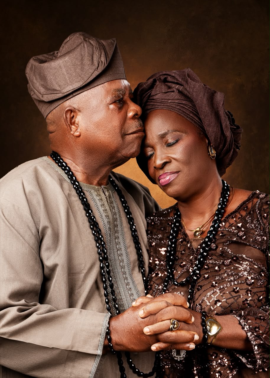 Elderly couple in brown traditional attire holding each other close
