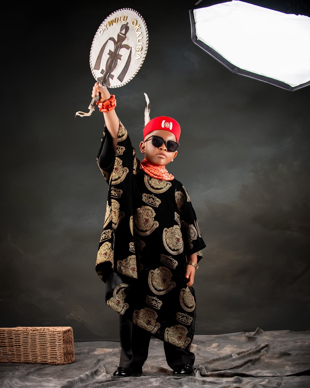 Young boy dressed as an Igbo chief holding a ceremonial fan