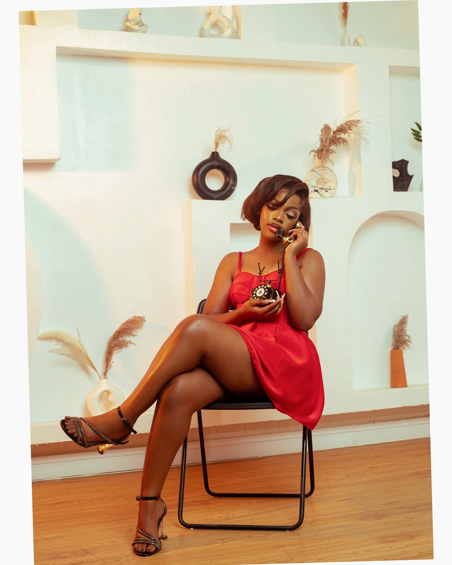 Woman in a red dress seated with a vintage rotary telephone